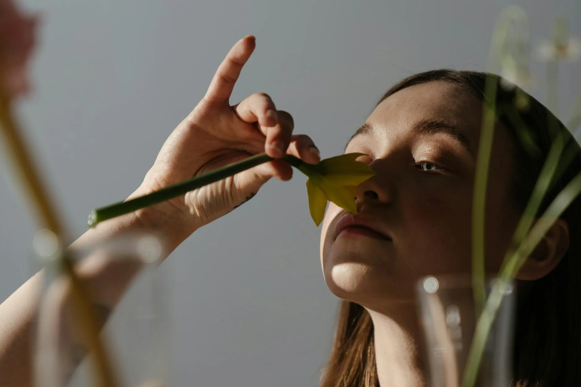 Person holding and smelling a flower stem.