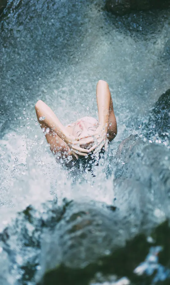 Person enjoying a waterfall splash.