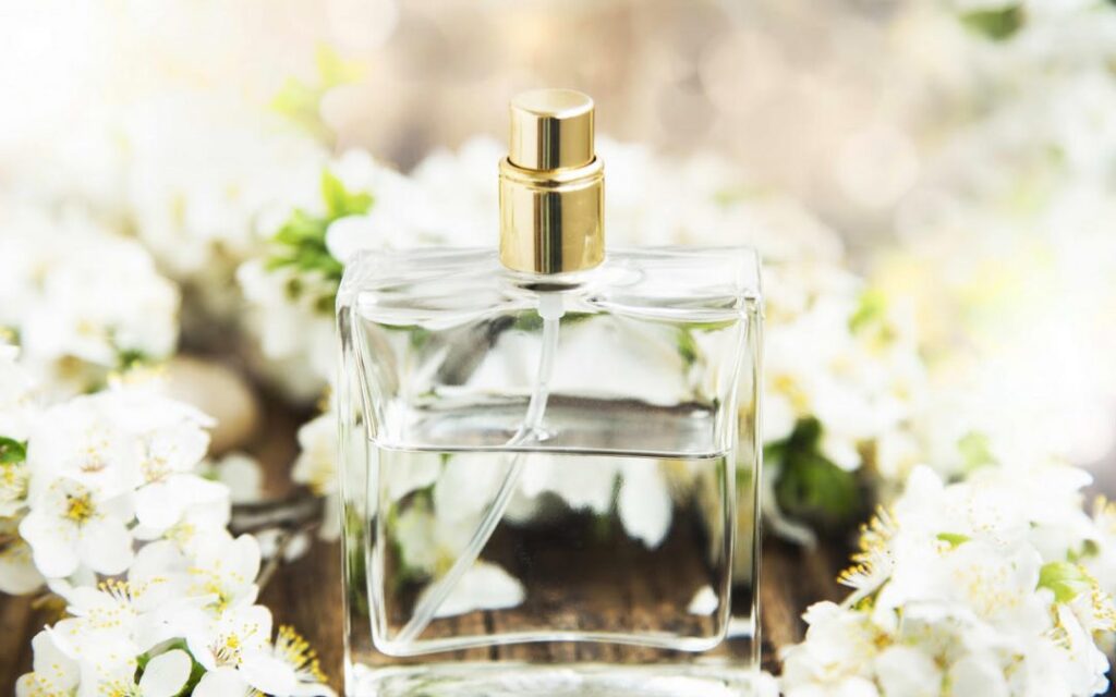 Perfume bottle surrounded by flowers.
