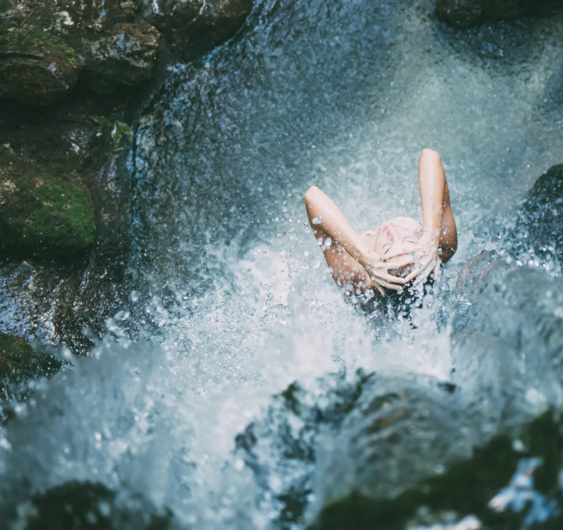 Person enjoying a waterfall's splash.