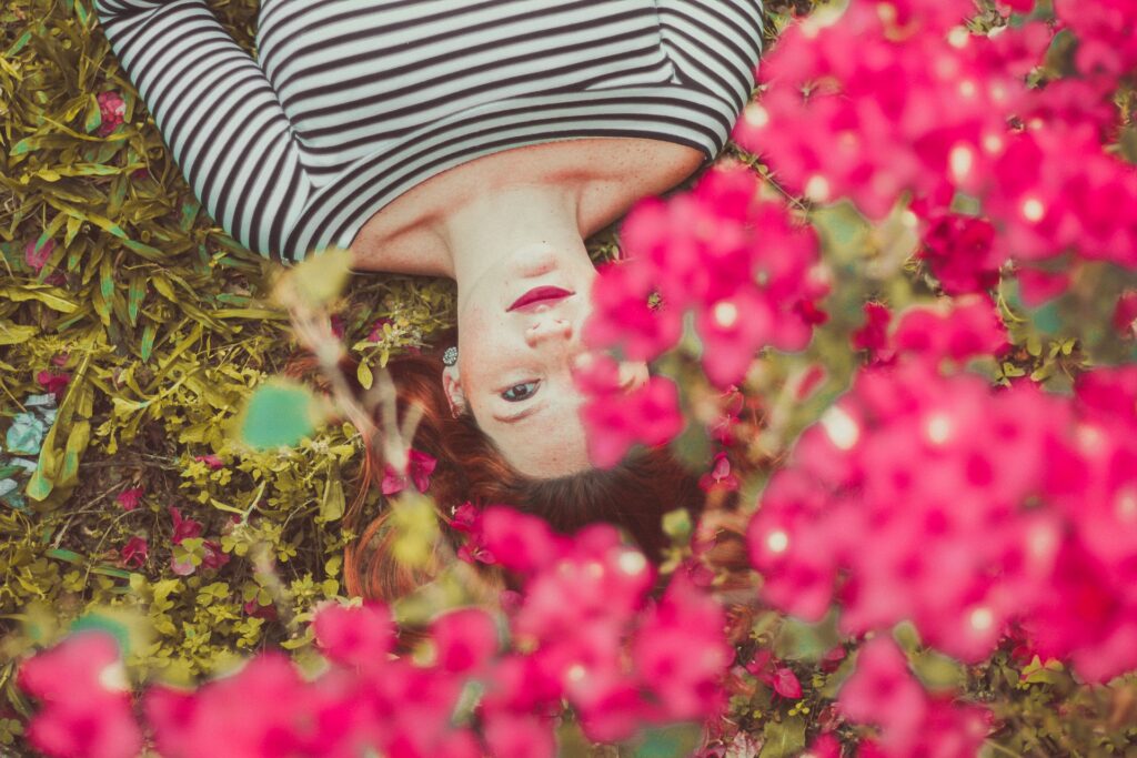 Woman lying among vibrant pink flowers.