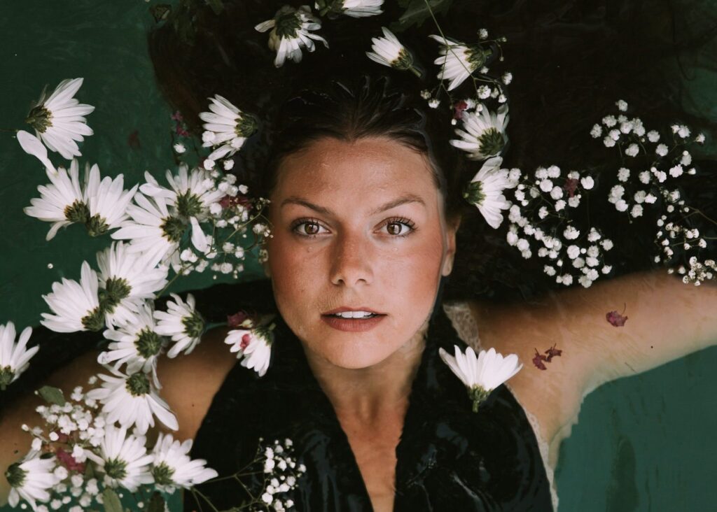 Woman surrounded by flowers in water.