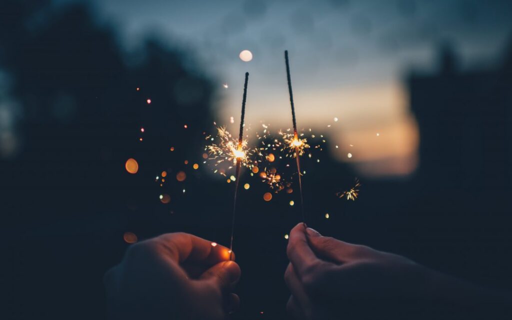 Hands holding sparklers at dusk